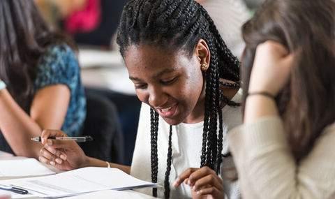 students sitting at a table in a classroom reviewing papers