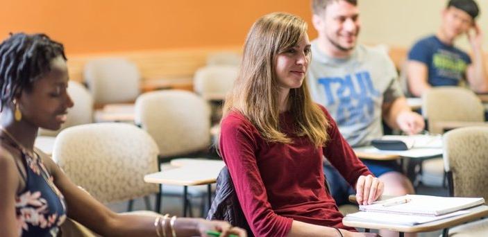 Students in class smiling at the professor